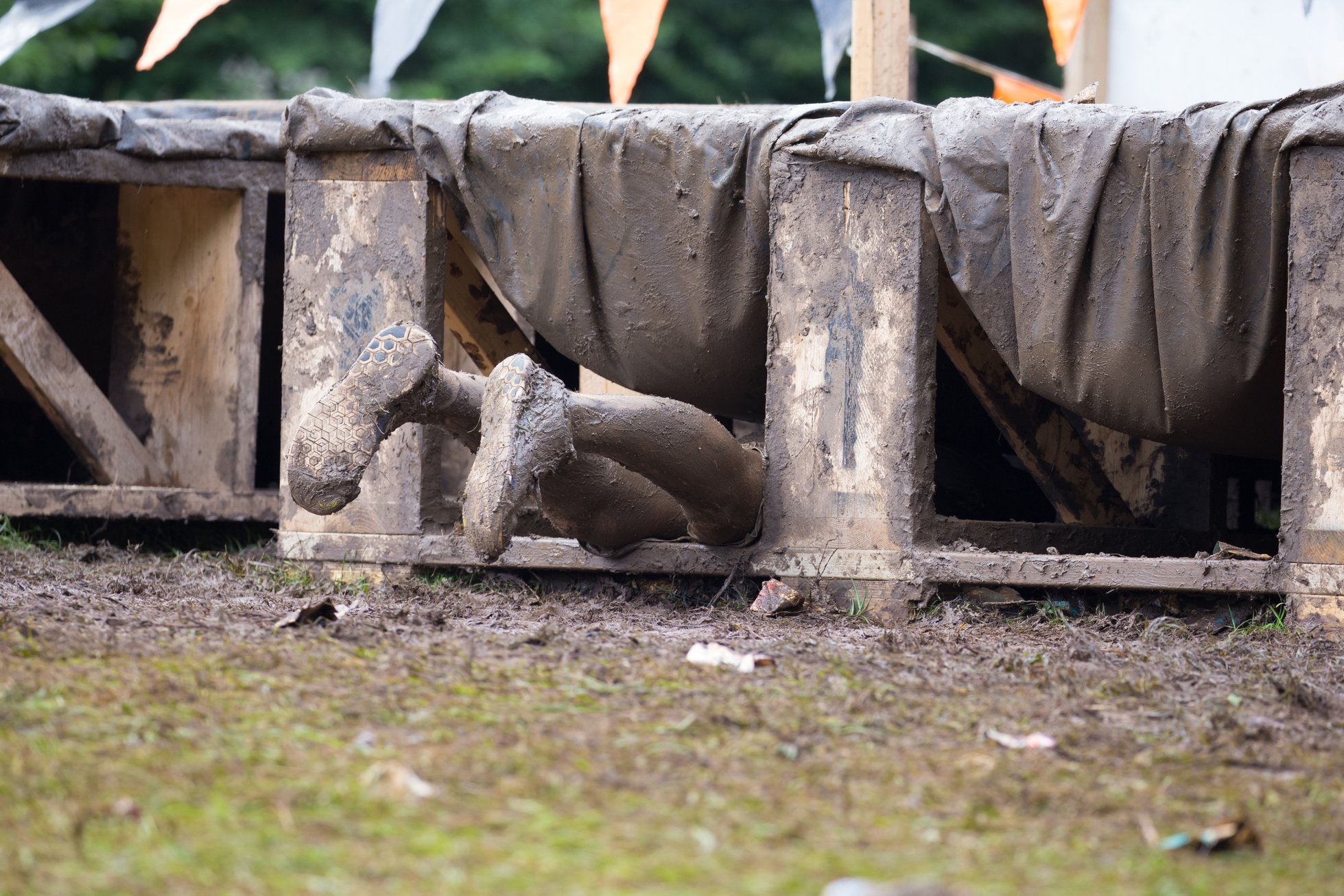 Muddy legs poking out of a Tough Mudder obstacle